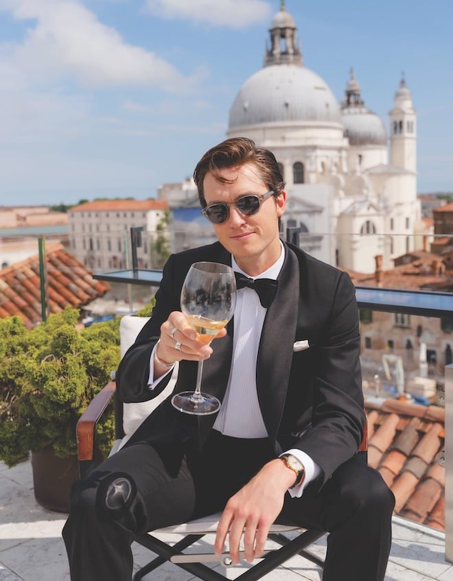 The groom sips on wine overlooking Venice, Italy, wearing men's watches for weddings.