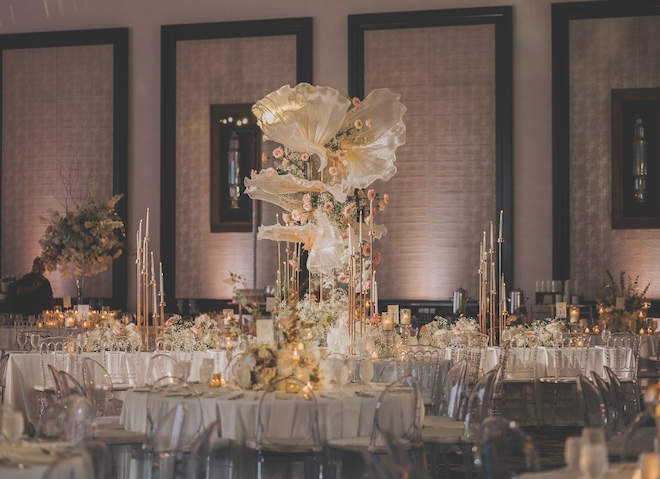 Pastel florals and candlelight decorate the reception tables in the ballroom.