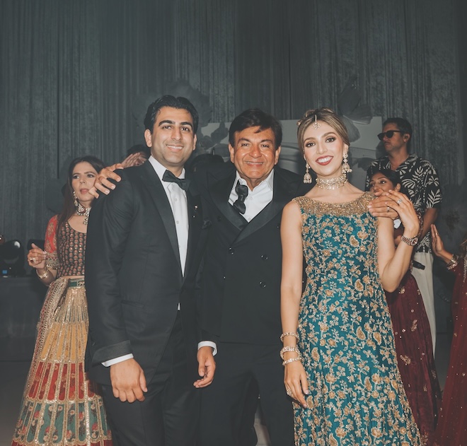 The bride and groom smile with a family member. 