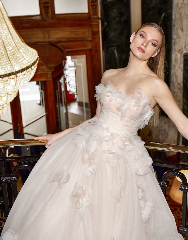 The bride wears a designer wedding gown by Pronovias with florals.