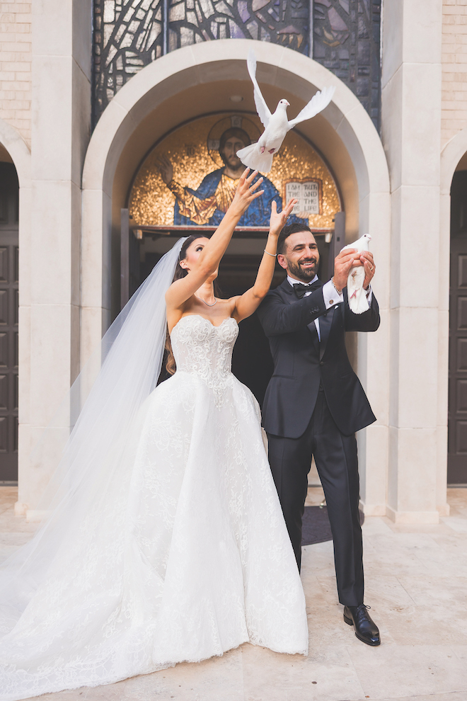 Newlyweds releasing doves in to the sky in front of the church before for their glamorous gold wedding at Houstonian.