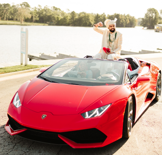 A groom celebrating in a red sports car for his baraat. 