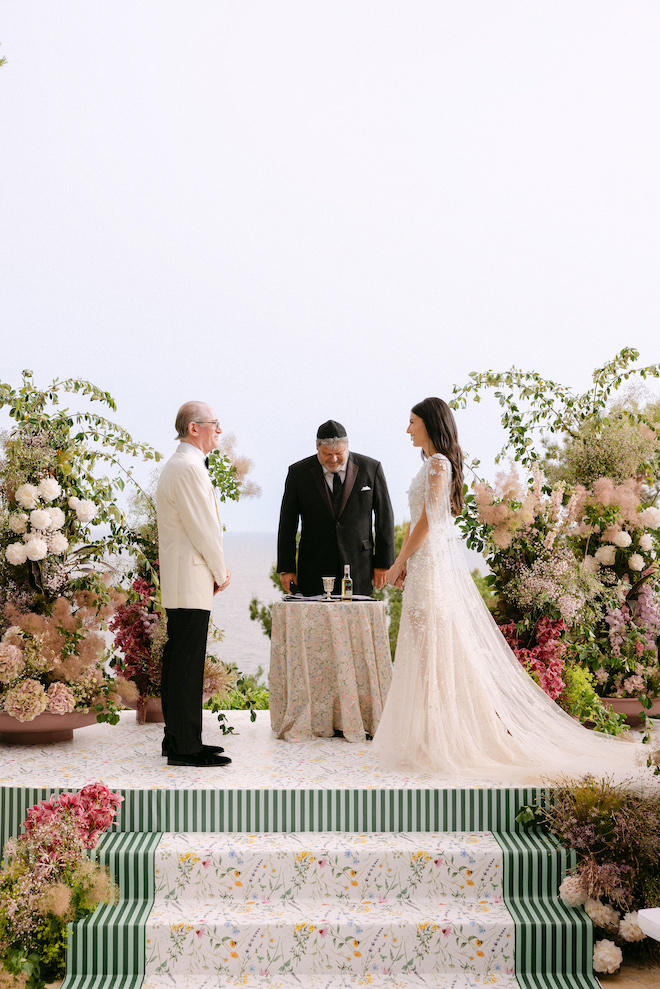 Bride and groom at the altar with colorful florals surrounding them and a drink inbetween them.