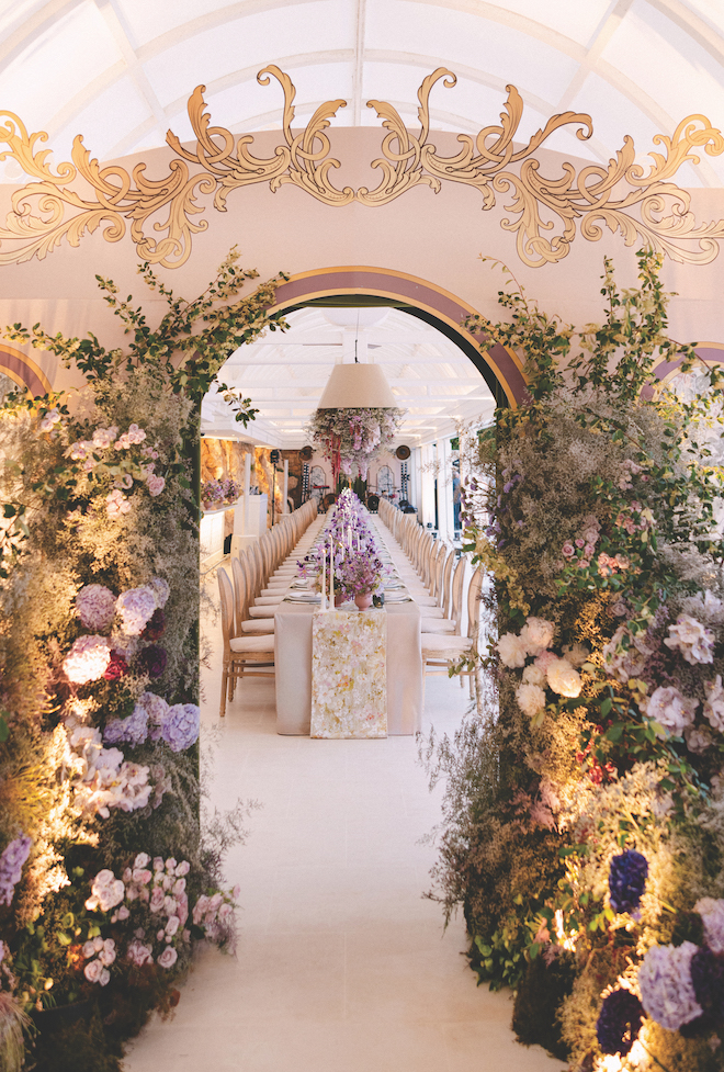 Arch door with colorful florals and greenery revealing the inside to reception table for French Riviera destination wedding.