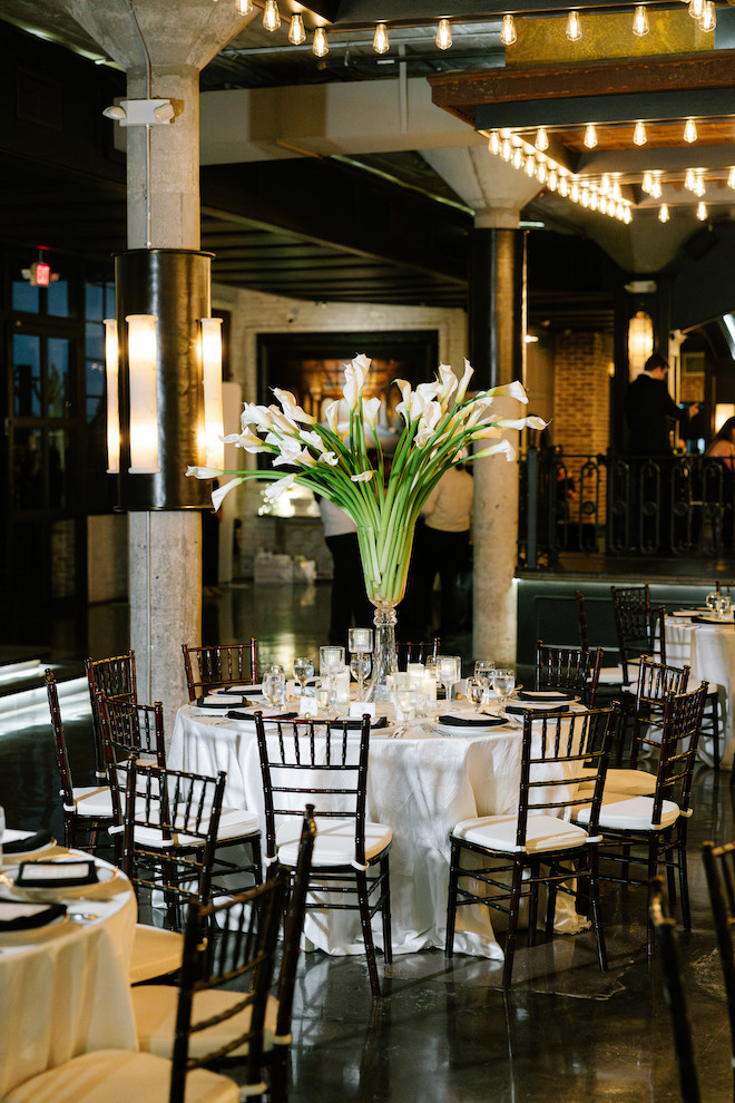 Reception table decor for spring wedding with white blooms showing candles and long stemmed tulips as centerpiece. 