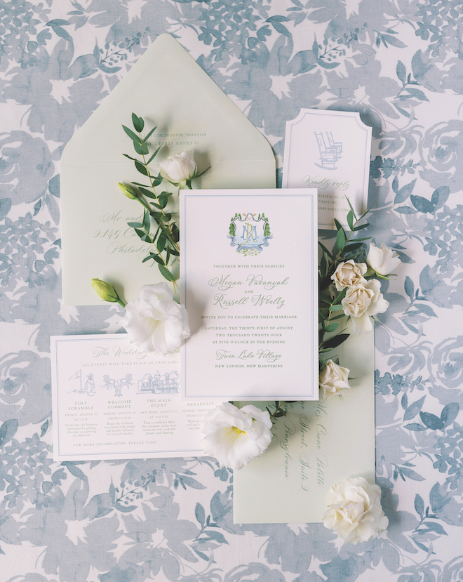 Light green detailed stationery with white florals and greenery around it with a blue and white floral detailed background.