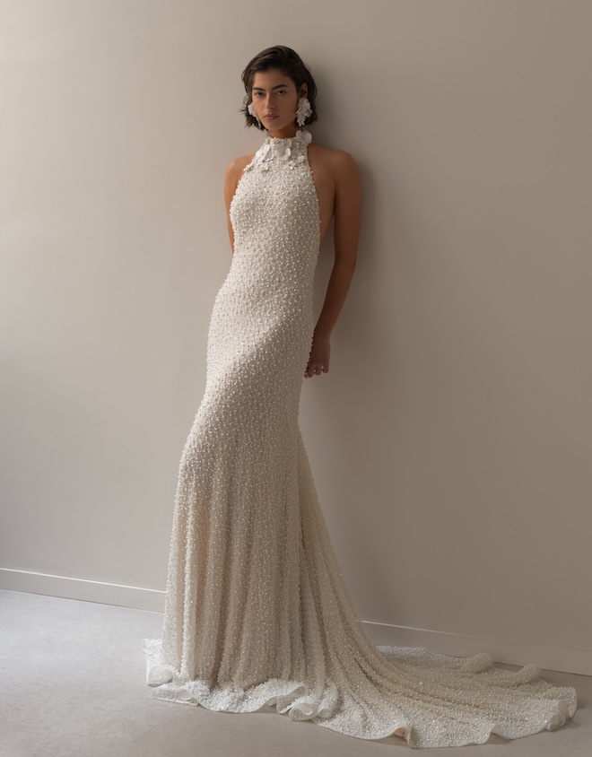 The model wears a pearl embellished halter wedding gown by Lihi Hod.