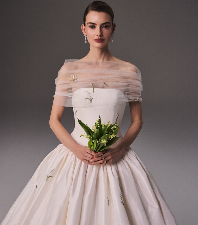 The model holds a bouquet of Lily of the Valley wearing a wedding gown by Phillipa Lepley. 