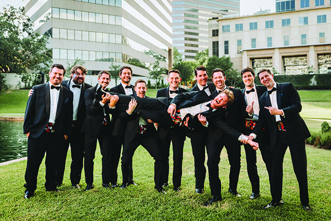 Groom being carried by groomsmen outside preparing for this Houston wedding band for their reception.