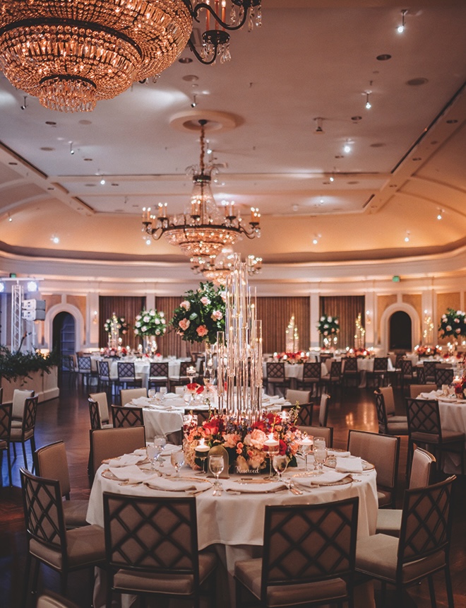Reception table decor with high candles, pink, green, and white florals  with white linen cloths preparing for this Houston wedding band to rock this blooming reception.