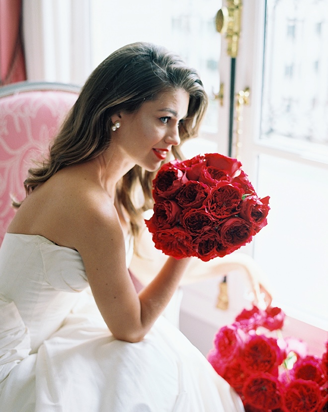 The bride holds her wedding bouquet of red ranunculus. 