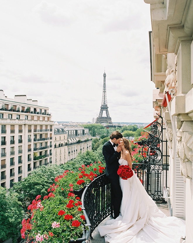 The couple kiss on the terrace of the Paris wedding editorial. 
