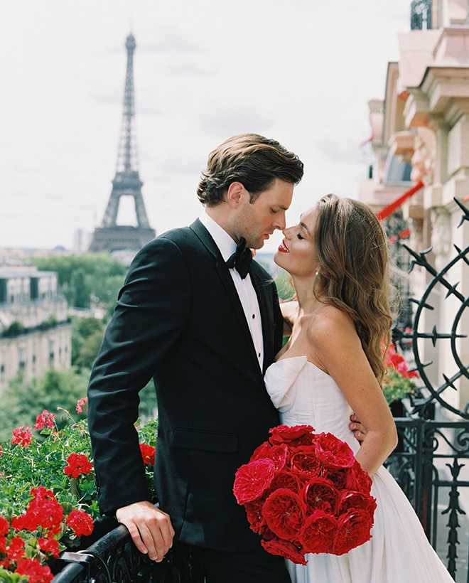 The bride and groom stand on a terrace in front of the Eiffel Tower in a Paris wedding editorial.