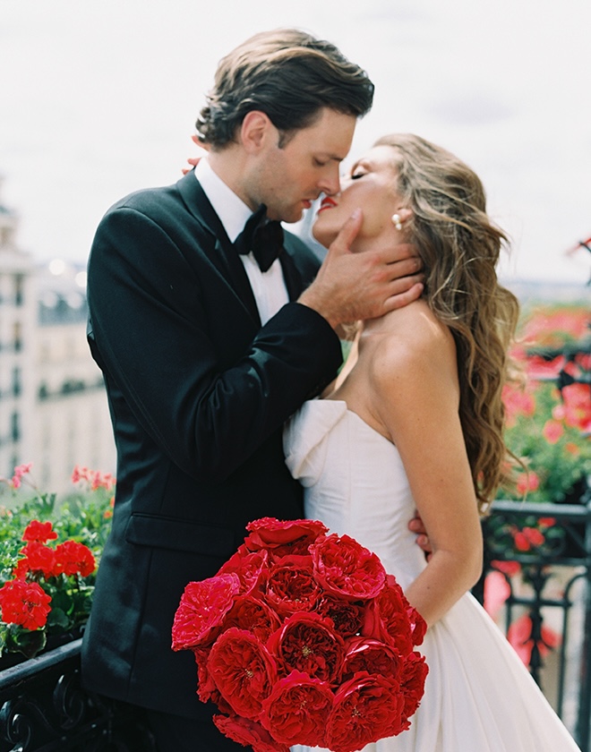 The bride and groom kiss on the terrace overlooking the Eiffel Tower. 
