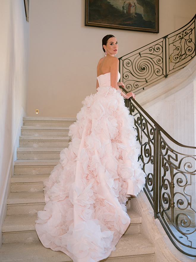 The model wears a light pink wedding gown with floral detailing. 