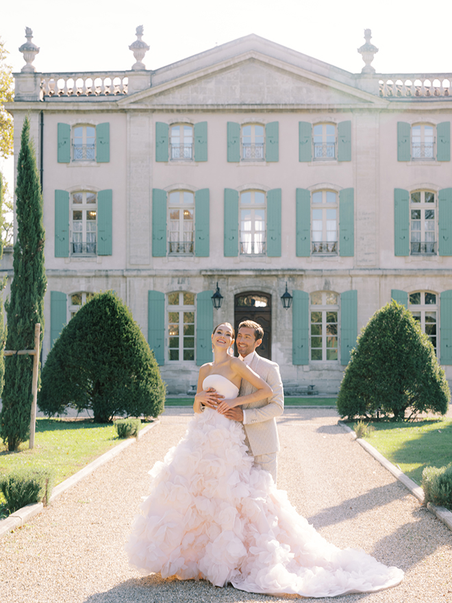 The couple smile outside a chateau in France. 