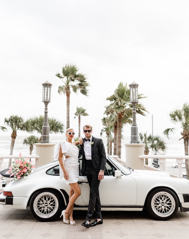 Bride and groom stand in front of the entrance of a wedding venue in Galveston. 