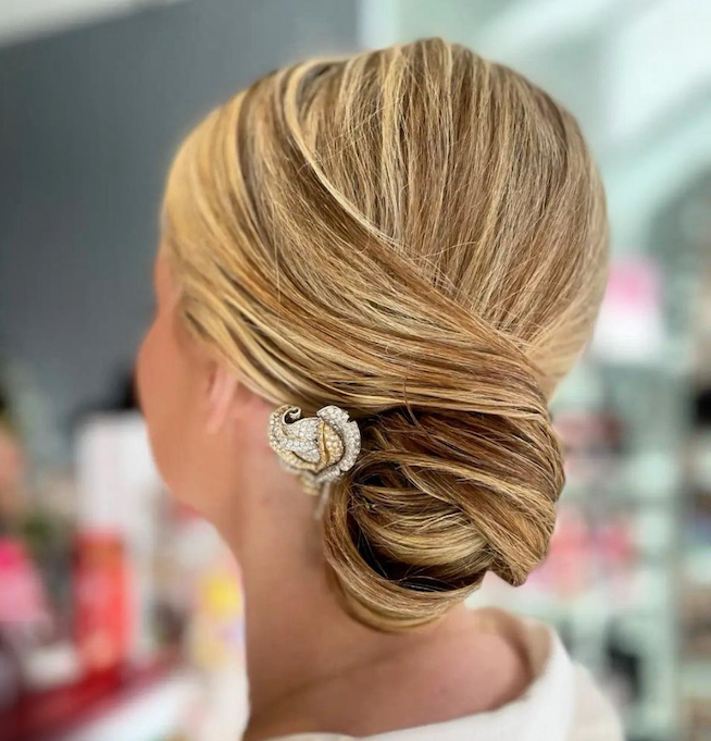 The woman has her hair up in an updo with a diamond hair piece. 