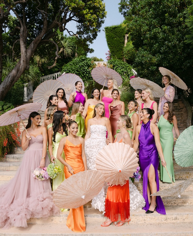 The bridesmaids surround the bride wearing colorful and vibrant dresses for the wedding day.