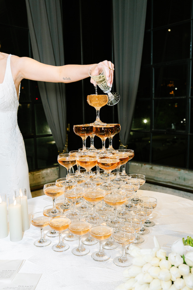 Tall champagne tower as bride is pouring top glass and filling others for Taylor Swift and Travis Kelce's wedding.