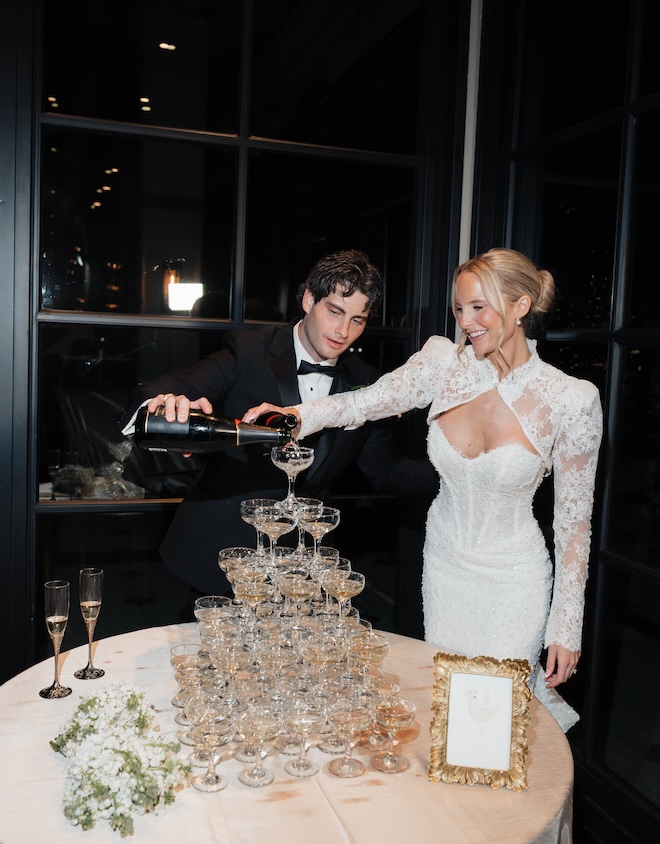 The bride and groom pour Champagne into coupe glasses formed into a tower. 