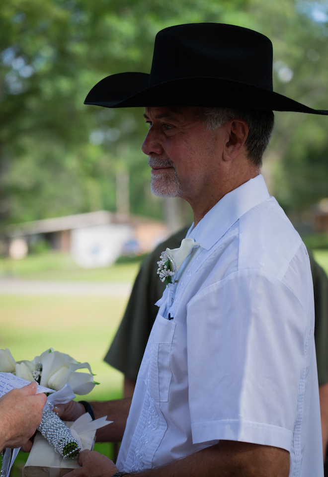 Groom staring at the bride wearing black cowboy hat at their Texas Wedding with an Intimate Wine Vineyard.