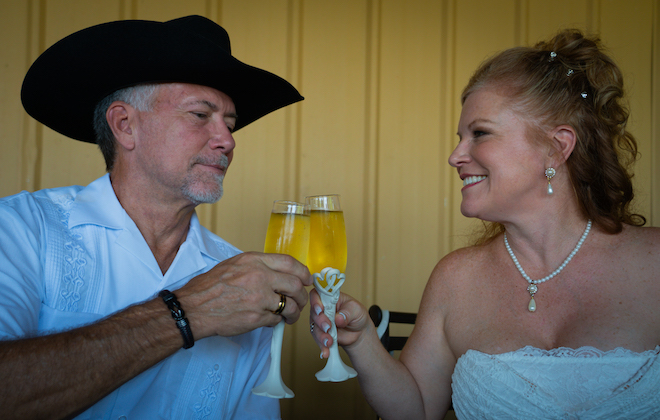 Newlyweds cheersing and looking at each other with a glass of champagne.