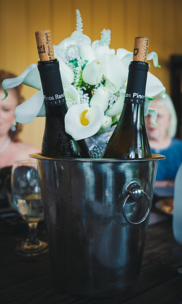 Champagne bottles in ice bucket with white bouquet in it.