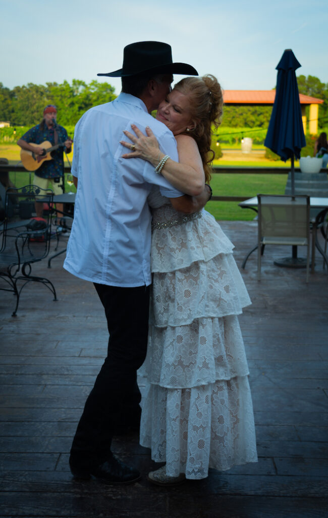 Bride and groom sharing a dance with guitarist playing live music in the background.