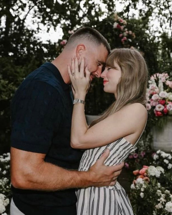 Taylor Swift and Travis Kelce holding each other in engagement photo in a lush floral garden.