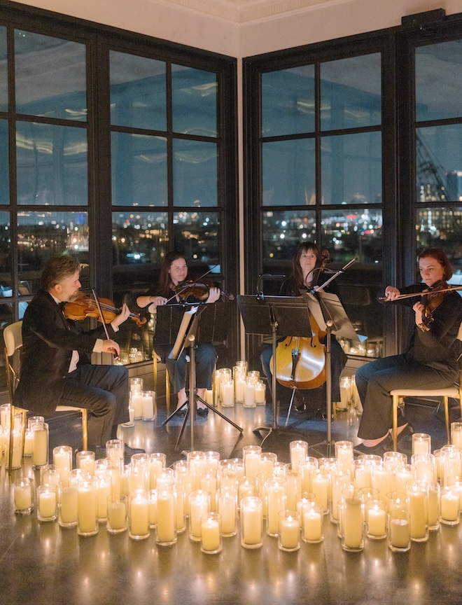 A string quartet play at a Houston wedding reception surrounded by candlelight. 
