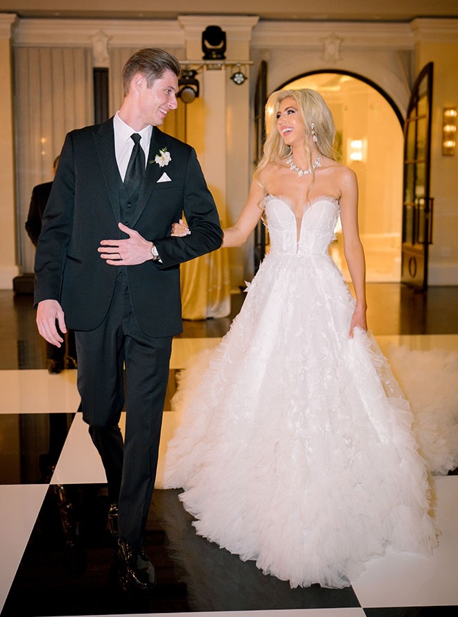 The bride and groom walk into their wedding reception. 