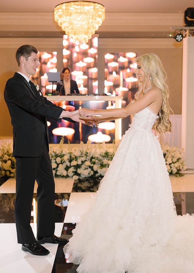 The couple dance at their wedding reception on a black and white checkered dance floor.