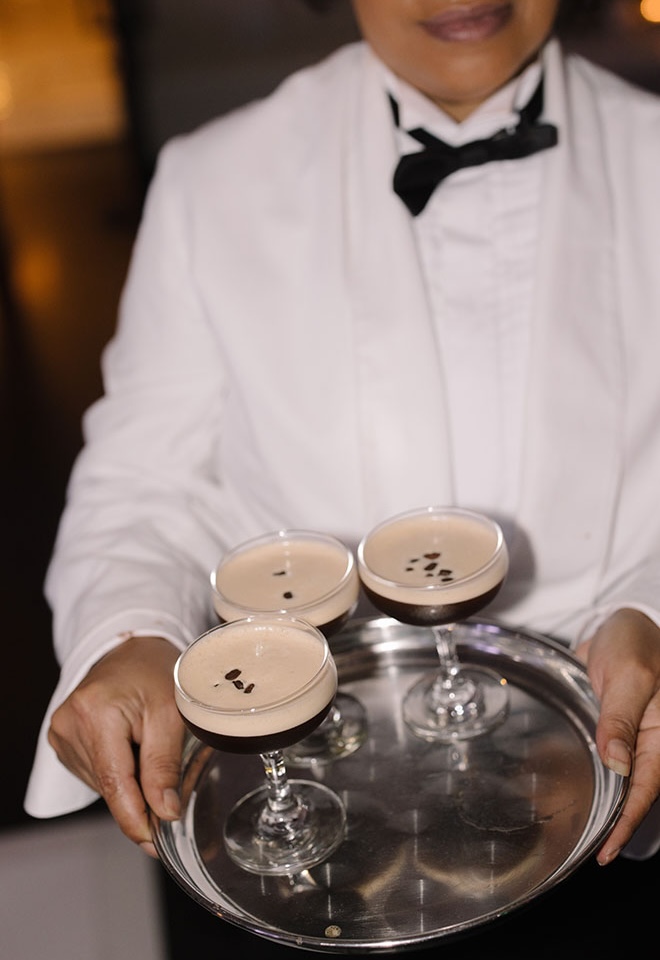 A waiter walks around the wedding reception serving espresso martinis on a silver platter.