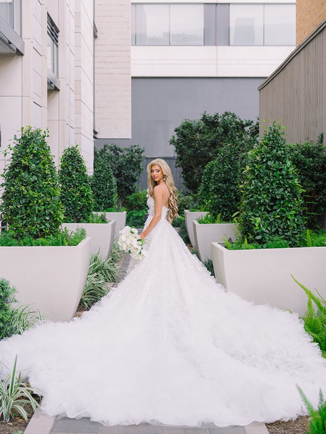 The bride stands outside holding her wedding bouquet.