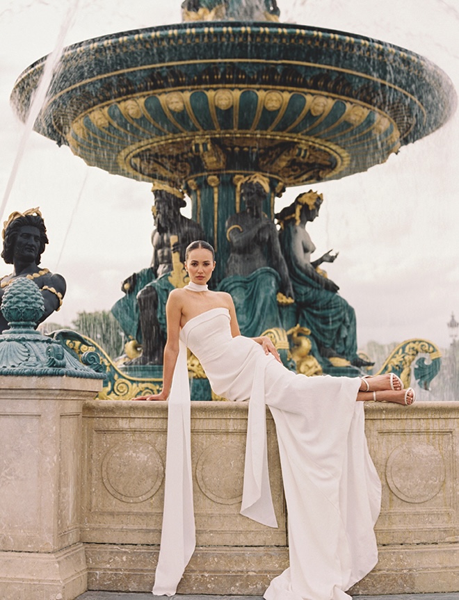 The bride sits on the ledge of a fountain for her Paris wedding photogaphy.