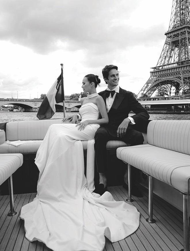 The bride and groom post in front of the Eiffel Tower while floating on a boat down the Seine river. 