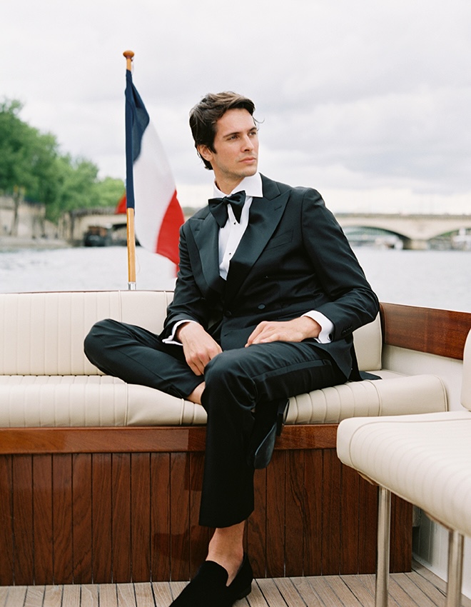 The grooms sits on the boat as he floats down the Seine.