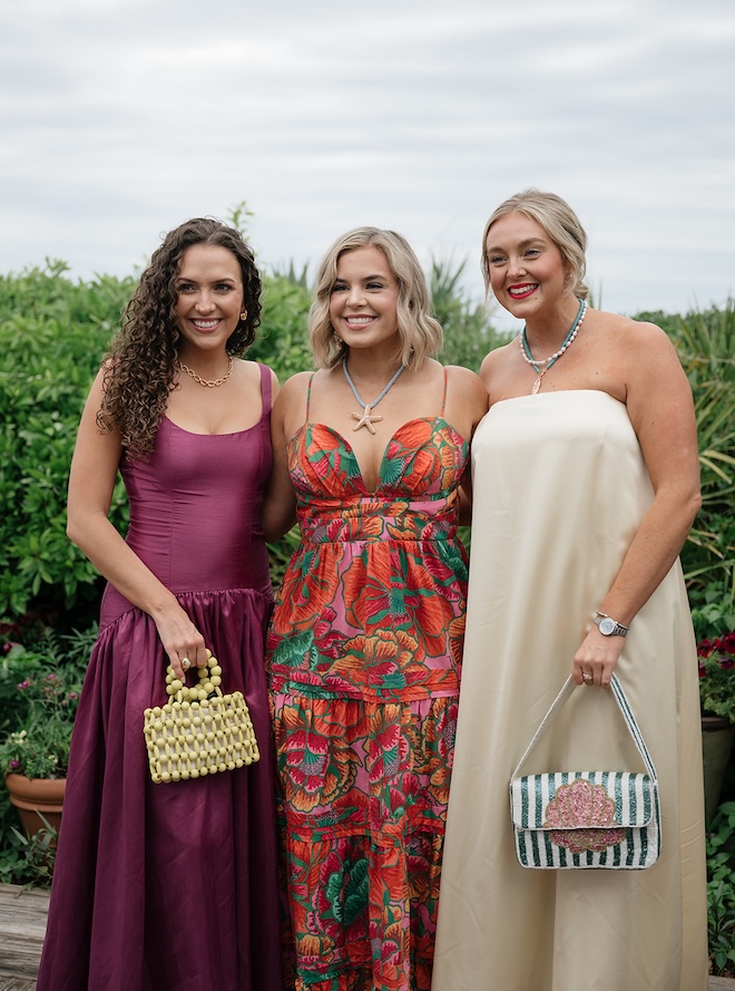 3 women standing in colorful dresses for tropical wedding.