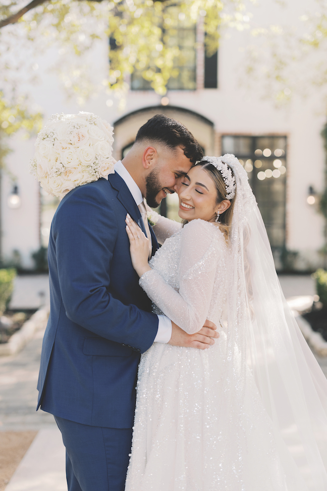 Bride and groom hugging and smiling together outside of stunning wedding venue.