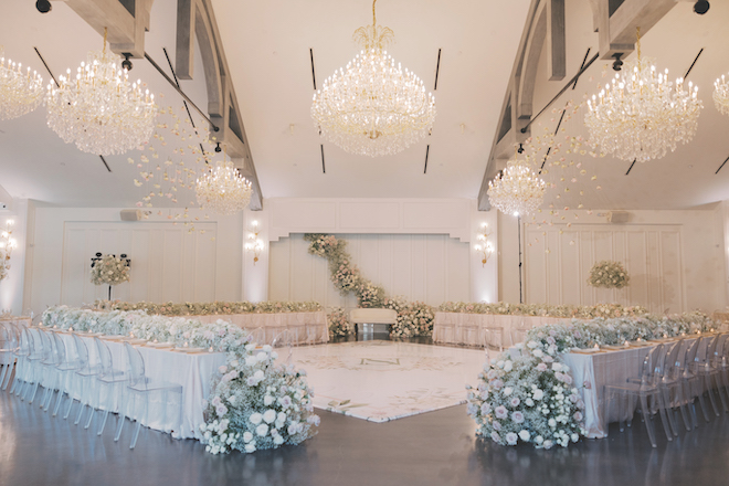 Reception decor with glass chandeliers with greenery and florals.