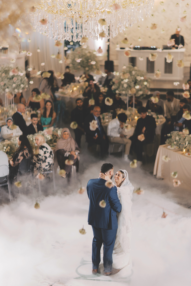 Bride and groom dancing on the dance floor surrounded by fog and falling roses.