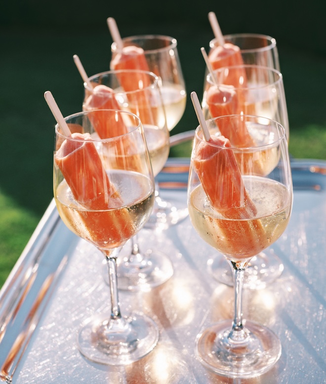 Orange popsicles are placed in a glasses are served during cocktail hour. 