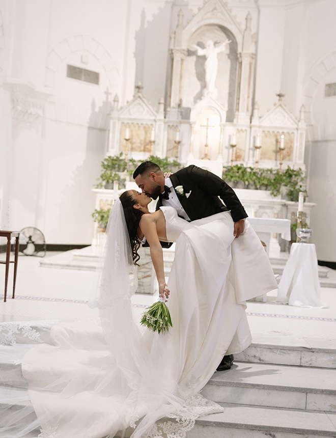 The groom dips the bride and gives her a kiss on the altar at their church ceremony in Galveston. 