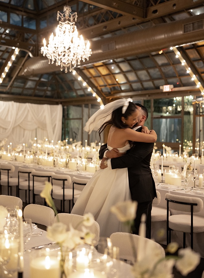 The groom twirls the bride around at their candlelit reception.
