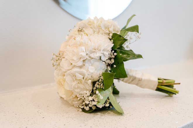 Classic white bouquet with greenery and ribbon wrapped stem.