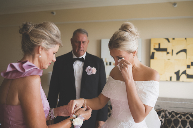 Bride crying while mom puts on her bracelet. 
