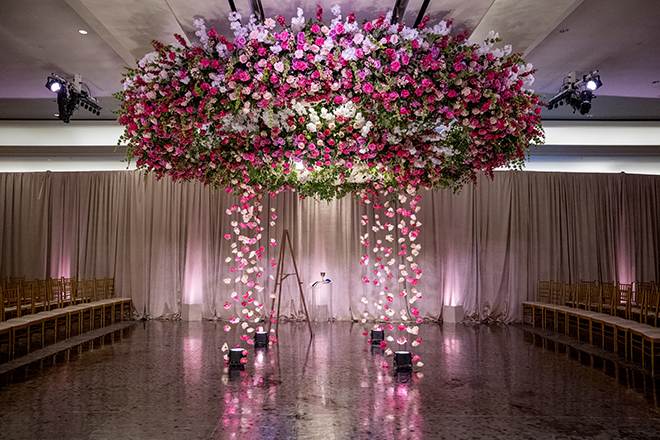Hot pink and light pink flowers decorate the chuppah at the Jewish wedding ceremony. 
