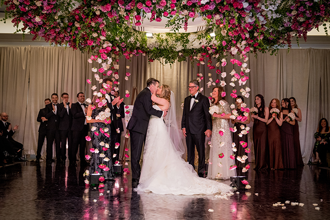The bride and groom share a kiss around a floral embellished chuppah at The Houstonian Hotel, Club and Spa.