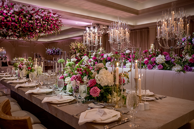 Pinks floral arrangements and white taper candles decorate the reception tables at the pink and brown wedding. 
